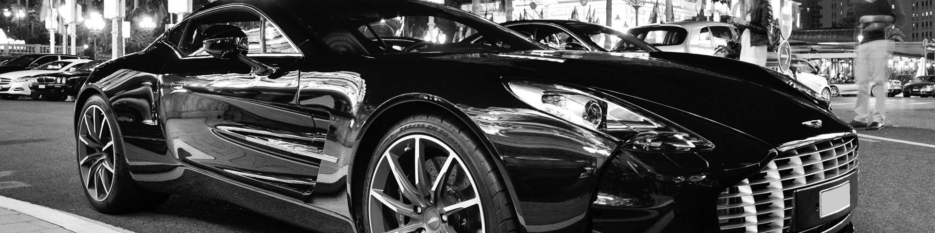 Black and white image of a black Aston Martin in a city centre